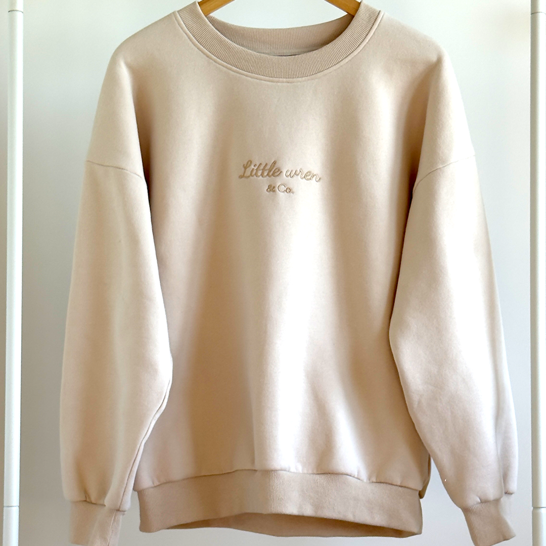 Beige sweatshirt with 'Little wear Co.' embroidery on a white background
