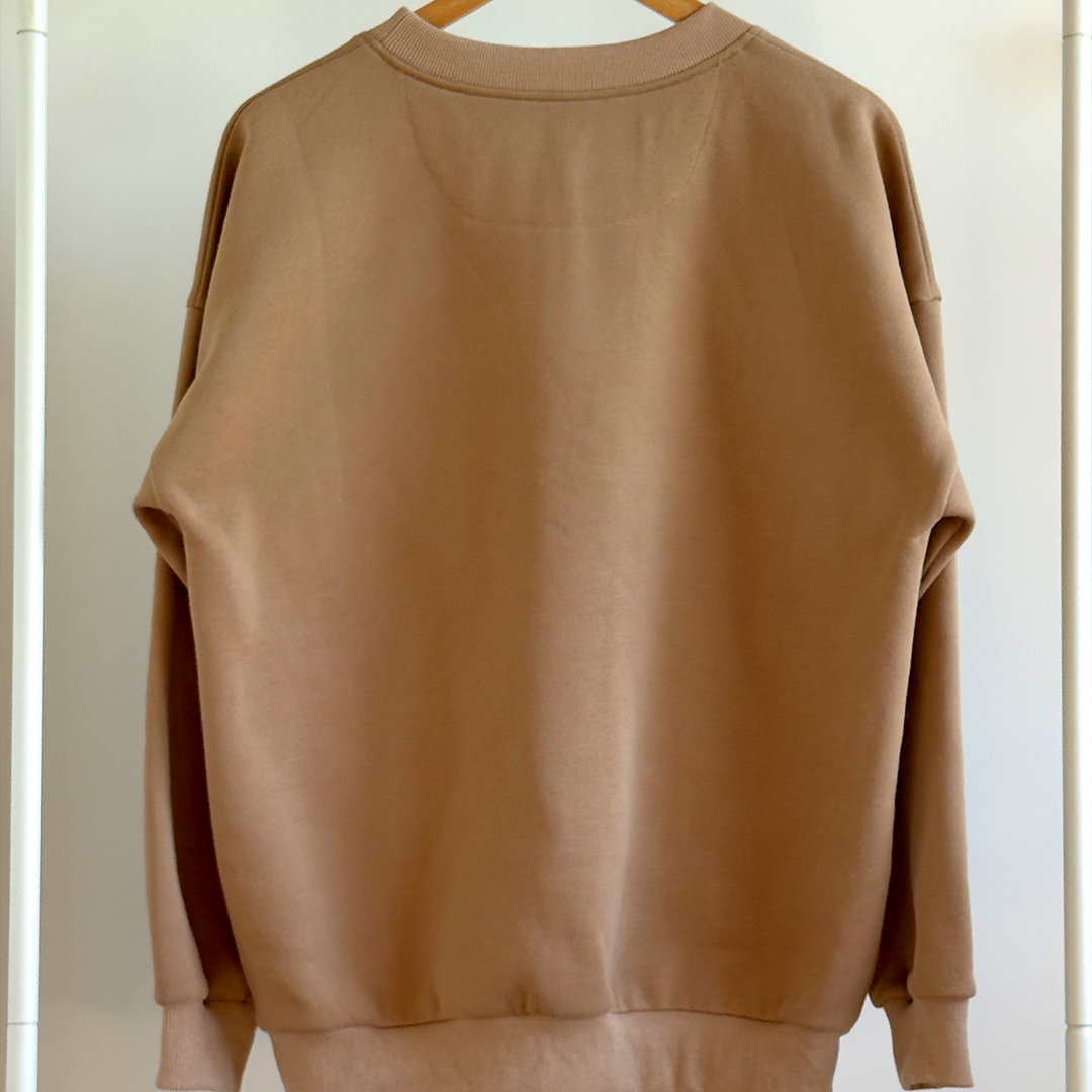 Brown sweatshirt on a hanger against a white wall