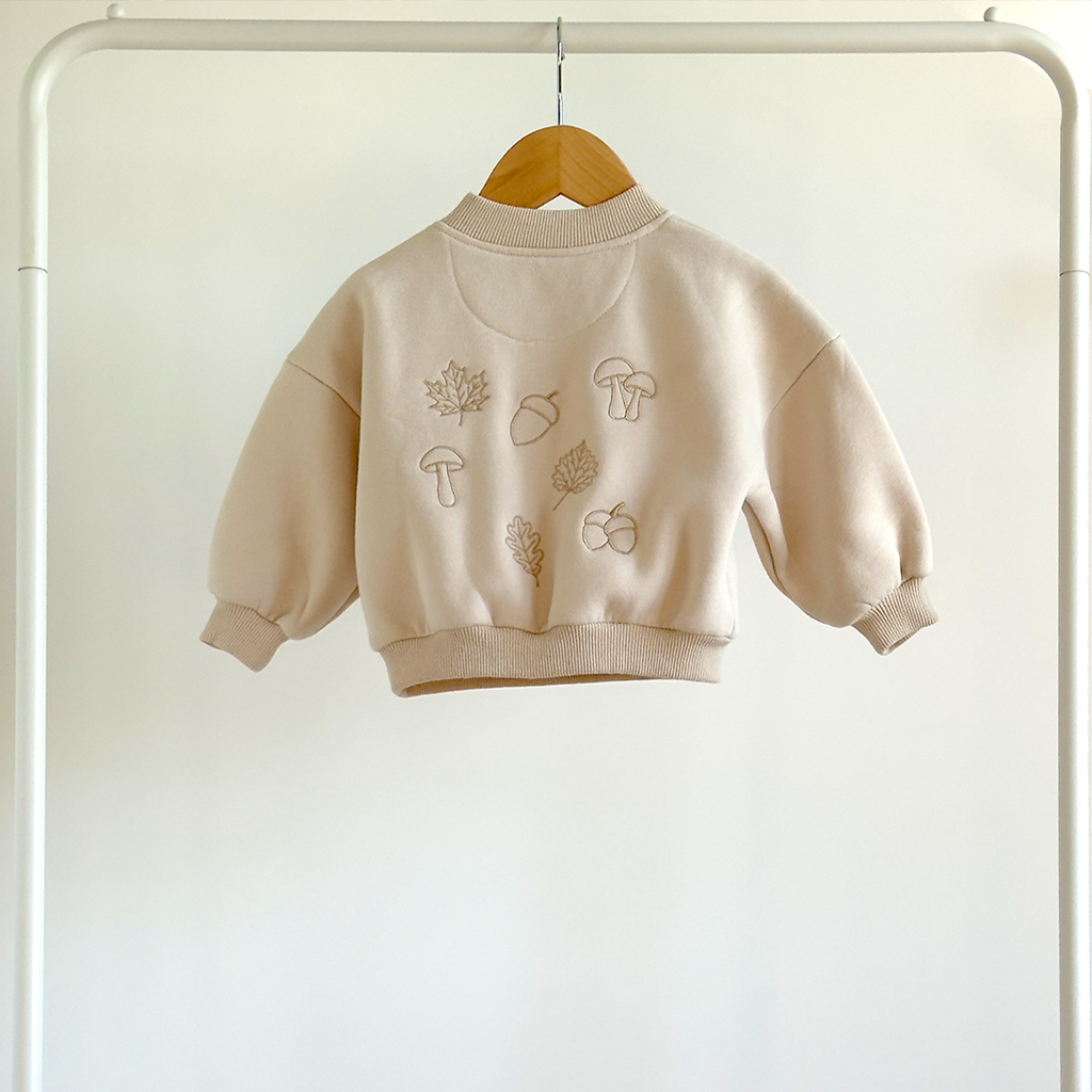 Beige sweatshirt with nature-themed embroidery on a white background