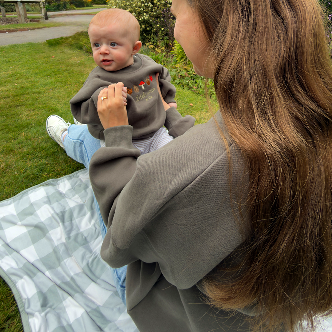 Woman holding a baby outdoors on a grassy area