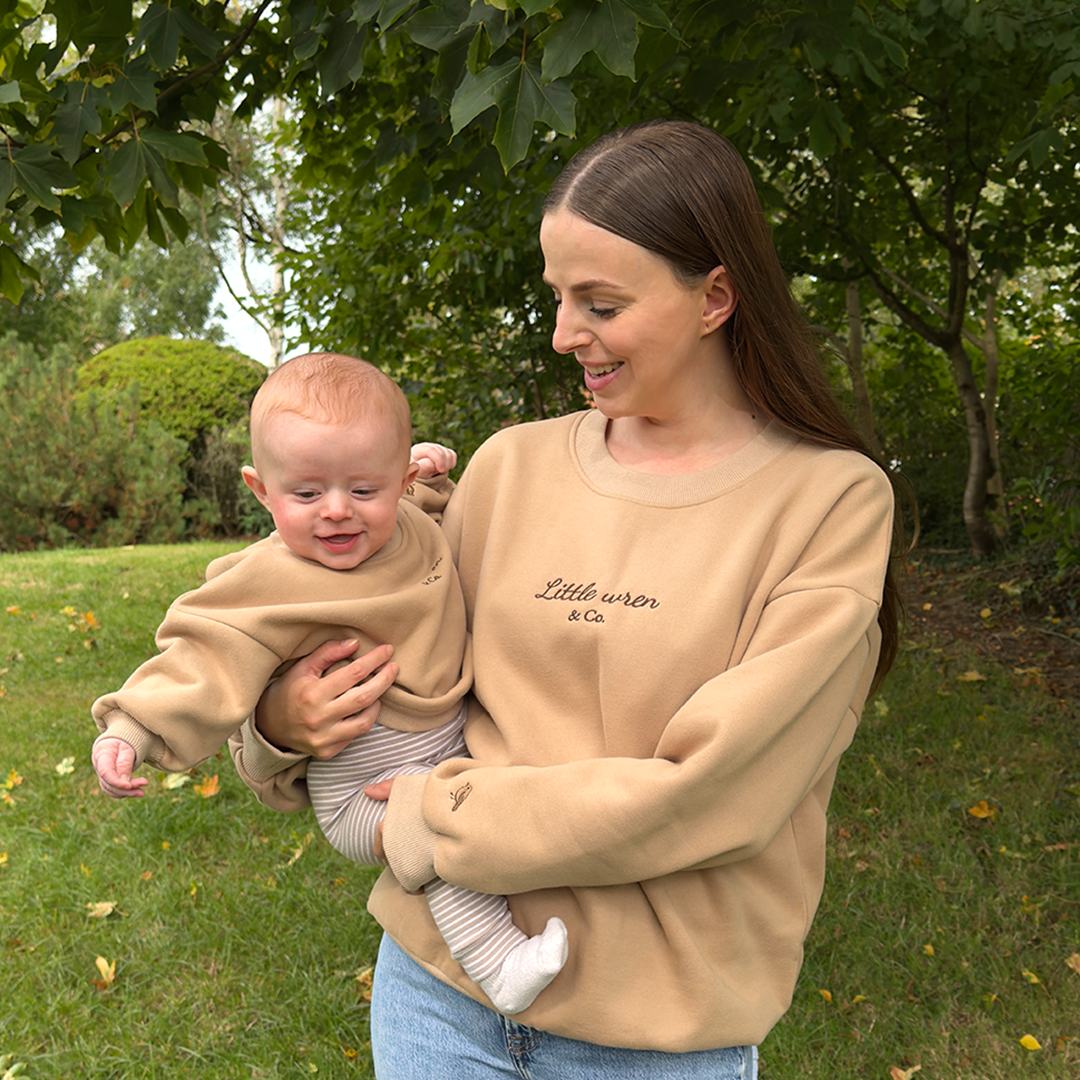 Woman holding a baby outdoors with greenery in the background
