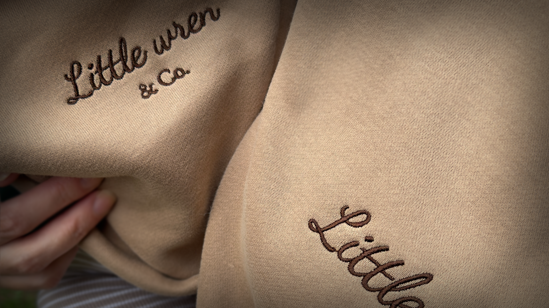 Close-up of beige fabric with 'Little wren & Co.' embroidery