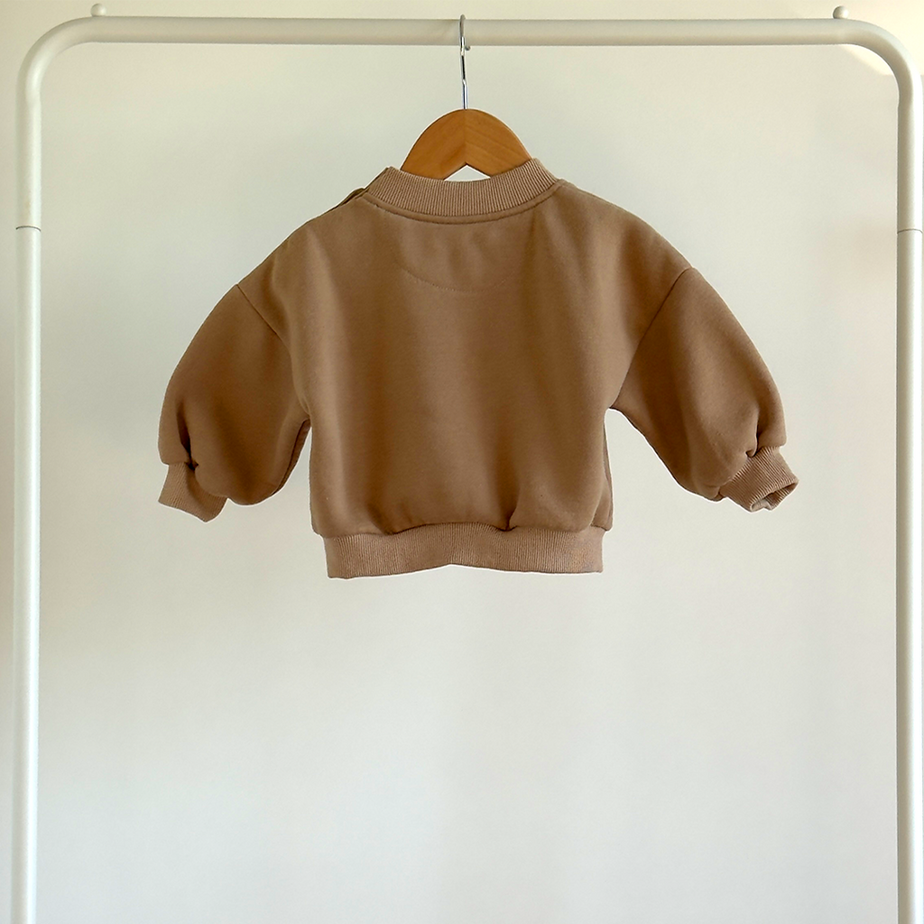 Brown baby's sweatshirt on a hanger against a white background