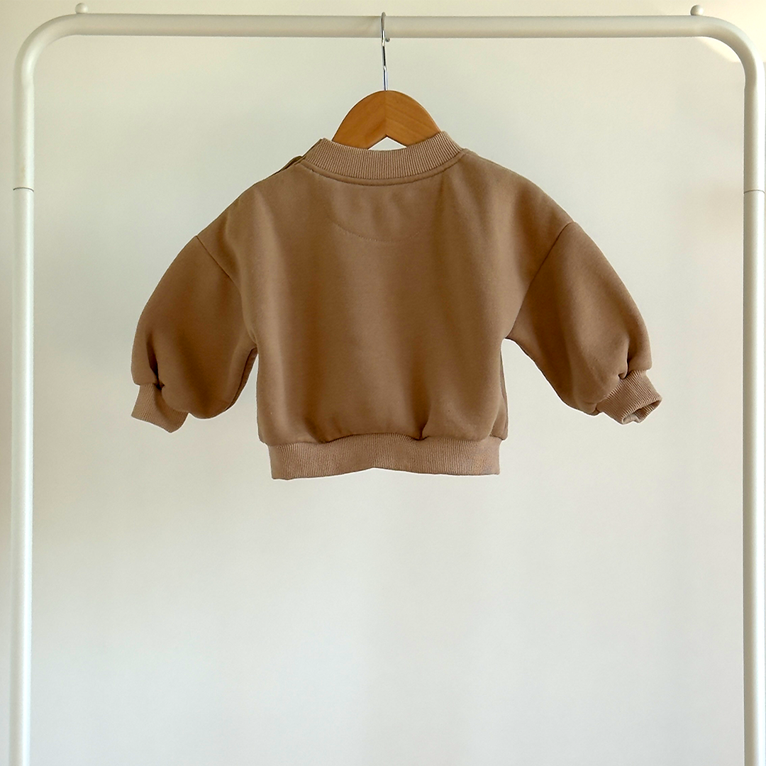 Brown baby's sweatshirt on a hanger against a white background